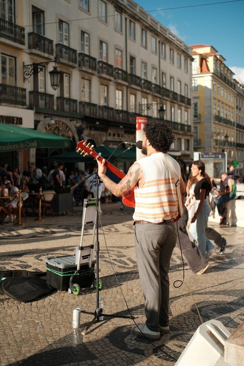 A street performer playing guitar on a cobblestone square in Lisbon, Portugal